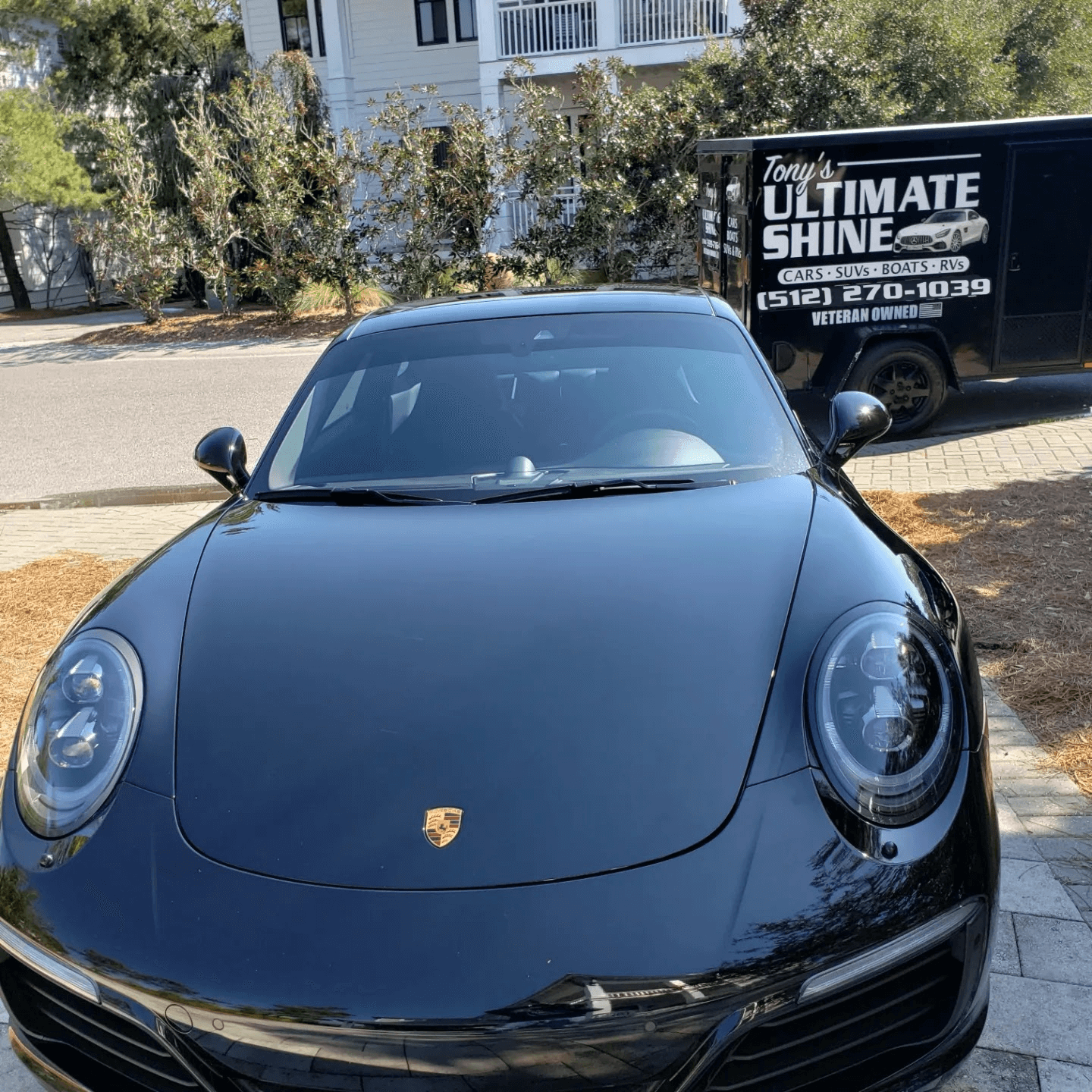 Detailed black Porsche with Tony’s Ultimate Shine trailer and phone number